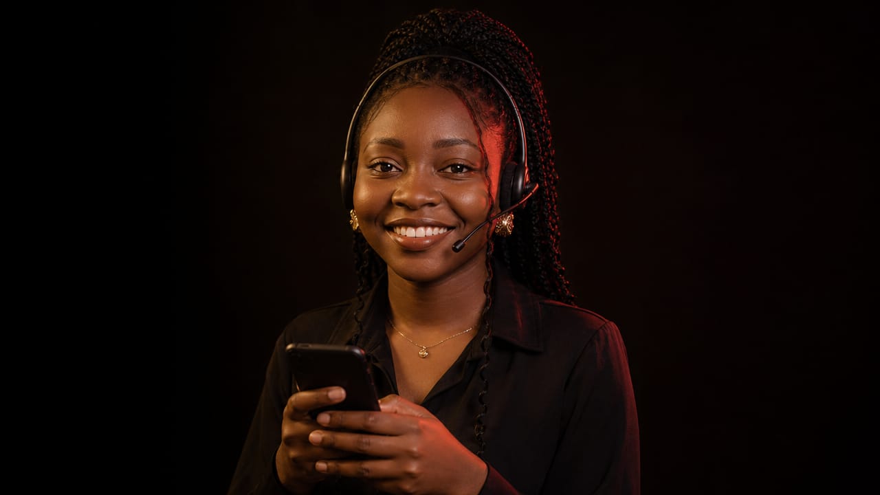 Une conseillère souriante avec un casque micro, téléphone en main